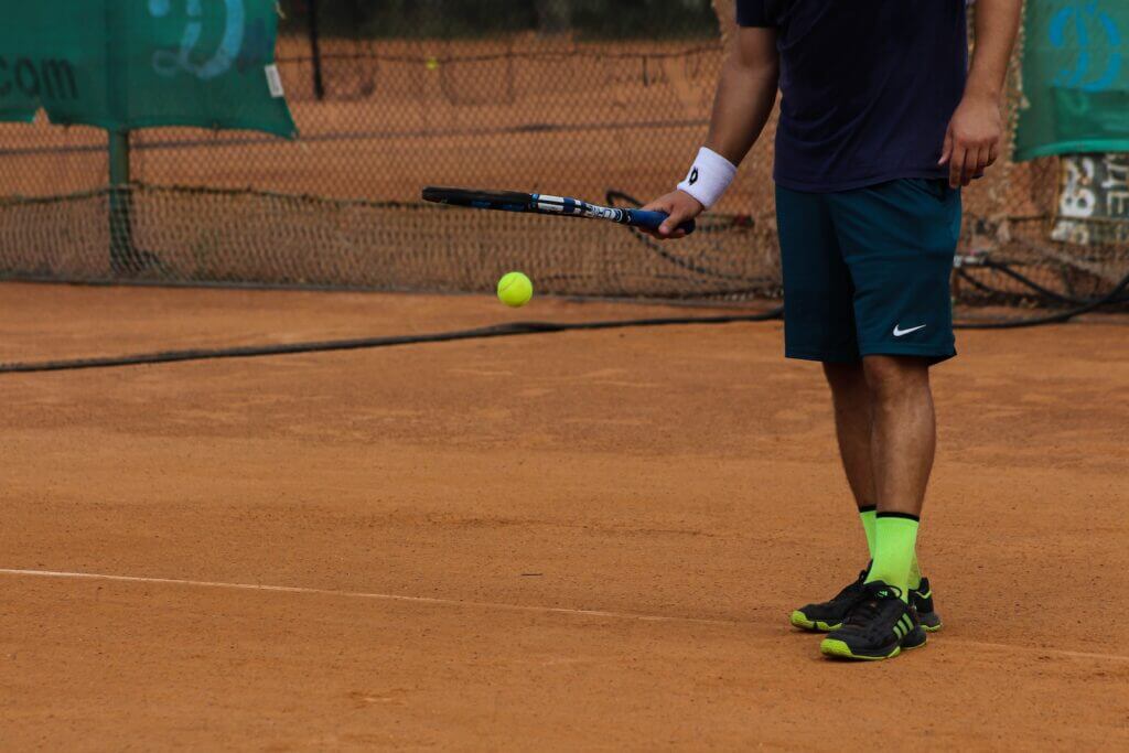 man in blue Nike shorts playing tennis