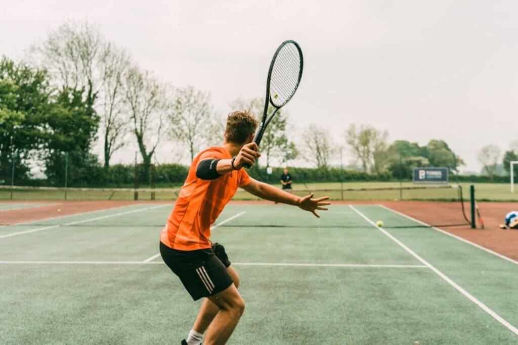 man in orange shirt playing tennis