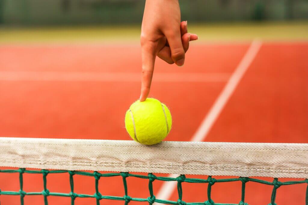 person holding tennis ball on net