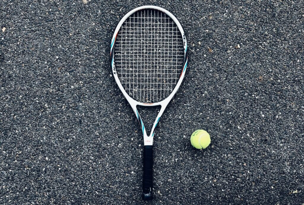 tennis racket and green tennis ball on surface